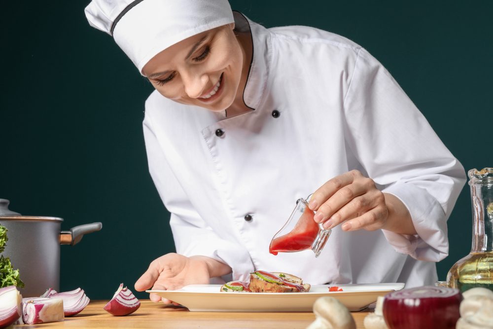 woman chef pouring sauce